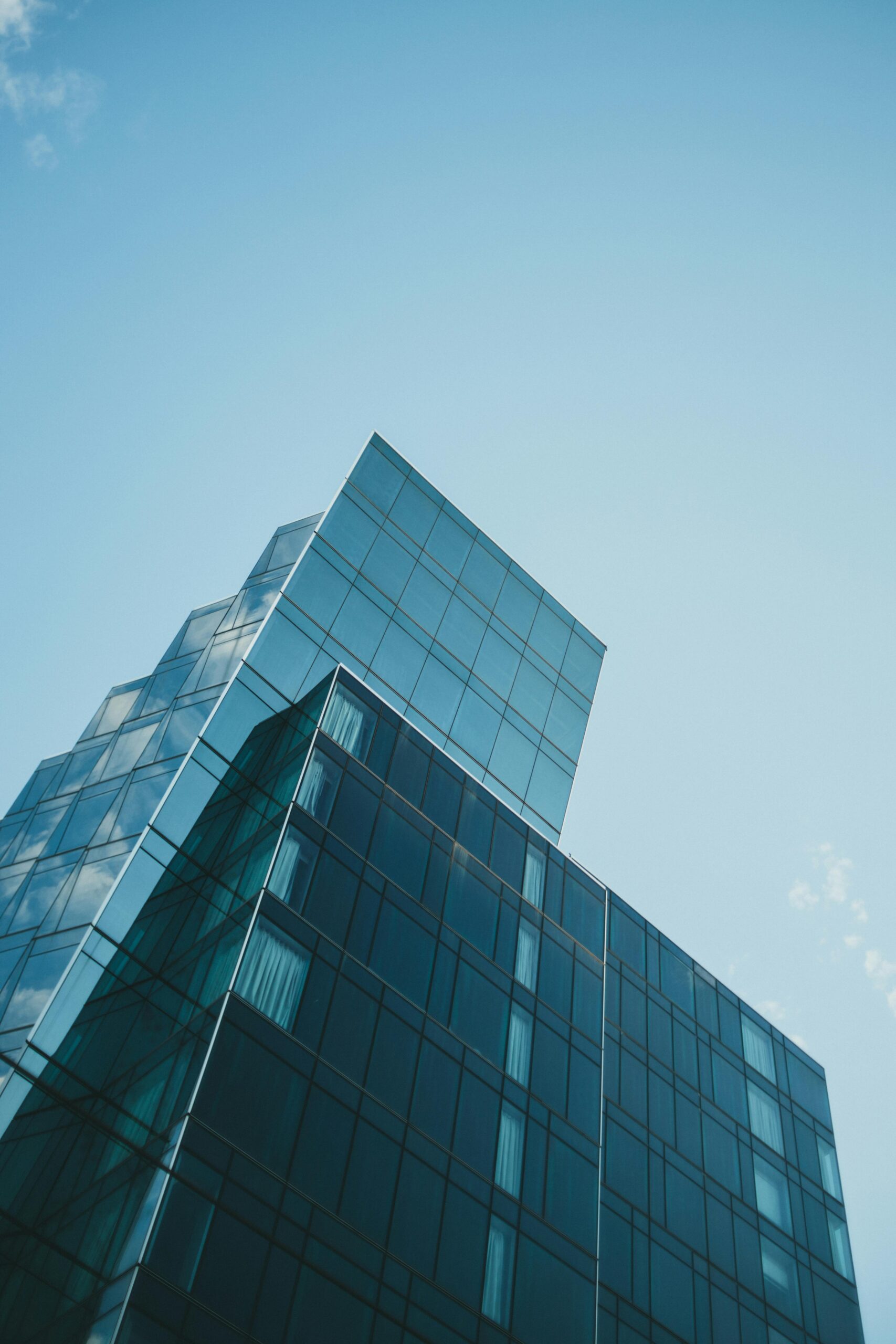 Contemporary glass skyscraper reaching into the clear blue sky, showcasing modern architectural design.
